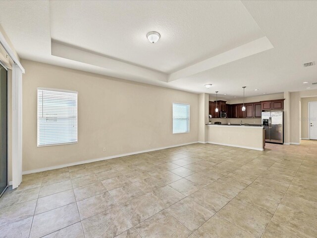 unfurnished living room with a wealth of natural light and a raised ceiling