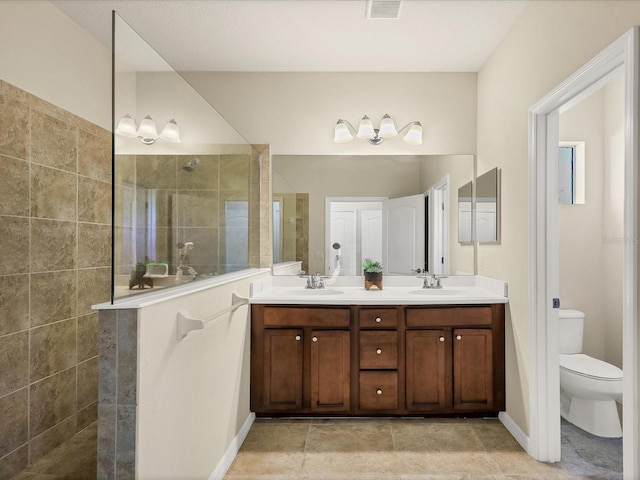 bathroom featuring vanity, tiled shower, and toilet
