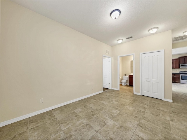 unfurnished bedroom with a closet, a textured ceiling, and ensuite bathroom