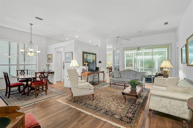 living room with ceiling fan with notable chandelier and light hardwood / wood-style flooring