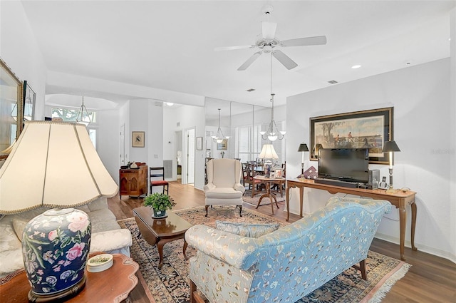 living room with hardwood / wood-style flooring and ceiling fan with notable chandelier