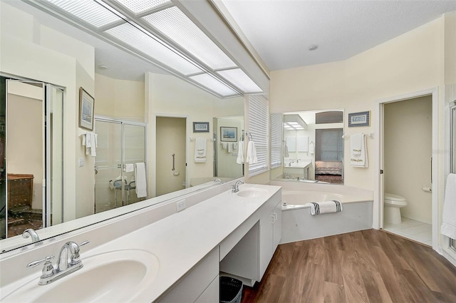 full bathroom with hardwood / wood-style flooring, vanity, toilet, and independent shower and bath