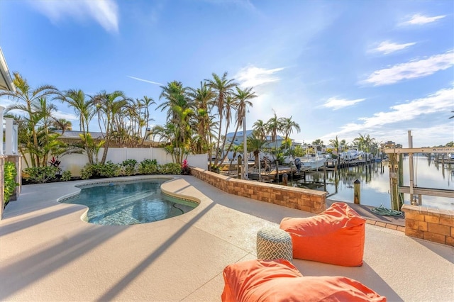 view of swimming pool featuring a water view, a patio area, and a boat dock