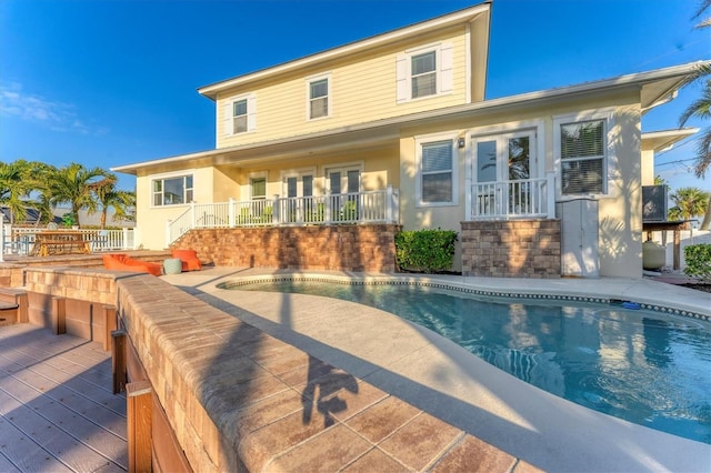 rear view of property featuring a patio, french doors, and a swimming pool side deck