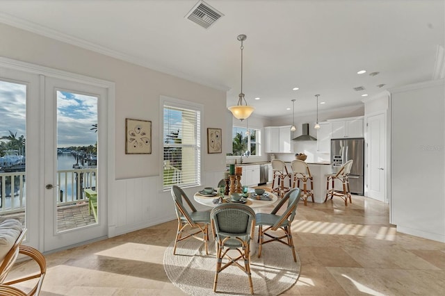 dining area featuring crown molding, a water view, and sink