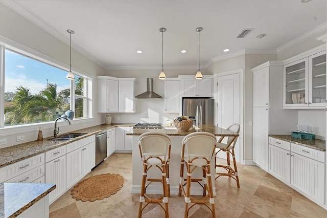 kitchen with wall chimney range hood, stainless steel appliances, sink, and stone counters