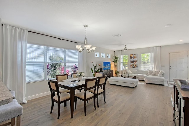 dining space featuring ceiling fan with notable chandelier and light hardwood / wood-style flooring