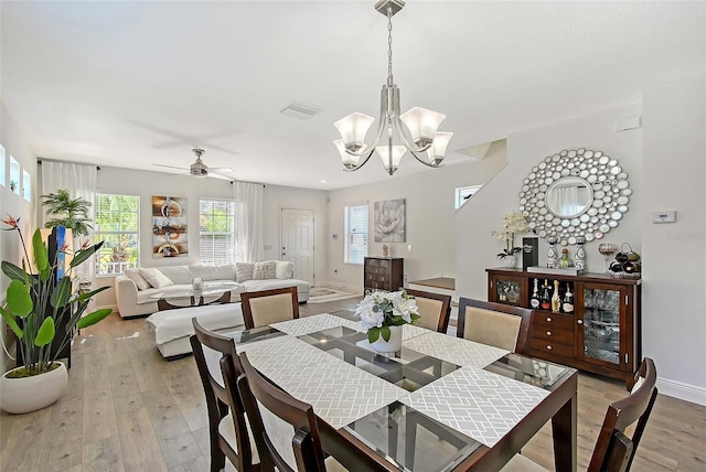 dining space with ceiling fan with notable chandelier and light hardwood / wood-style floors