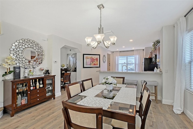 dining area featuring a notable chandelier, light hardwood / wood-style flooring, and sink