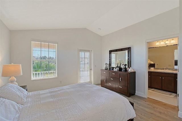 bedroom with vaulted ceiling, sink, connected bathroom, and light hardwood / wood-style floors