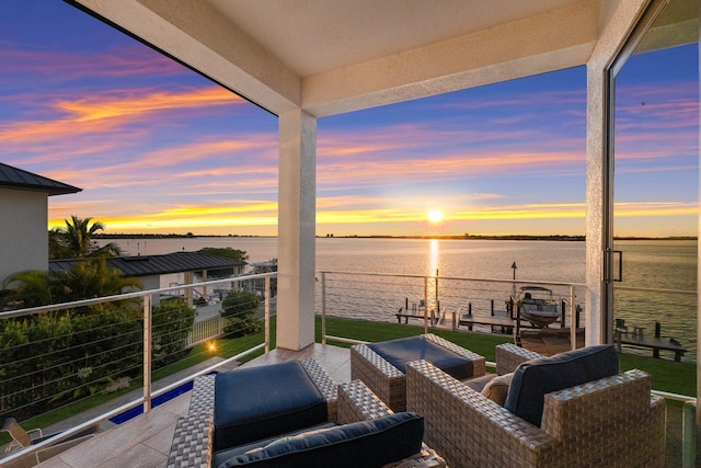 patio terrace at dusk featuring outdoor lounge area, a balcony, and a water view