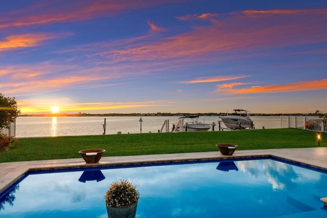 pool at dusk featuring a water view, a lawn, and a boat dock