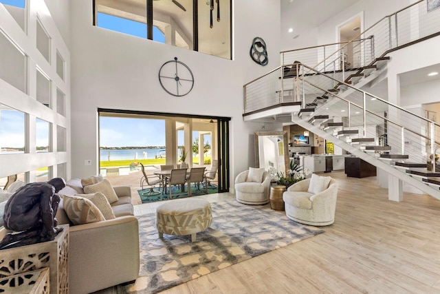 living room with a high ceiling, wood-type flooring, and a water view