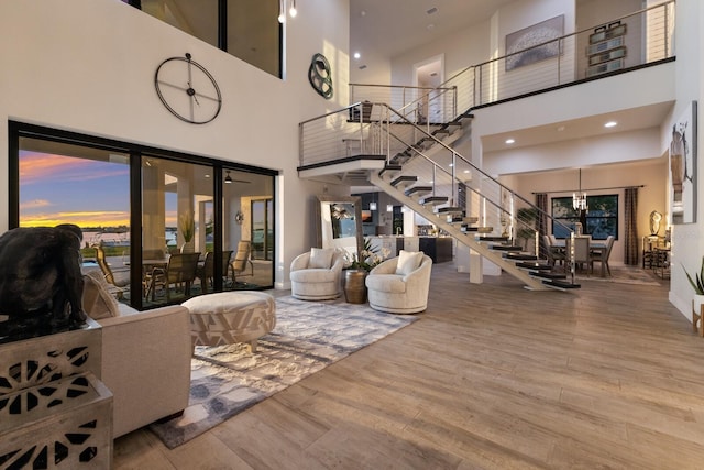 living room with hardwood / wood-style flooring, a towering ceiling, and a chandelier