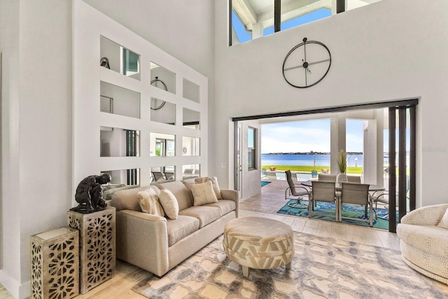 living room featuring a towering ceiling, a wealth of natural light, and a water view