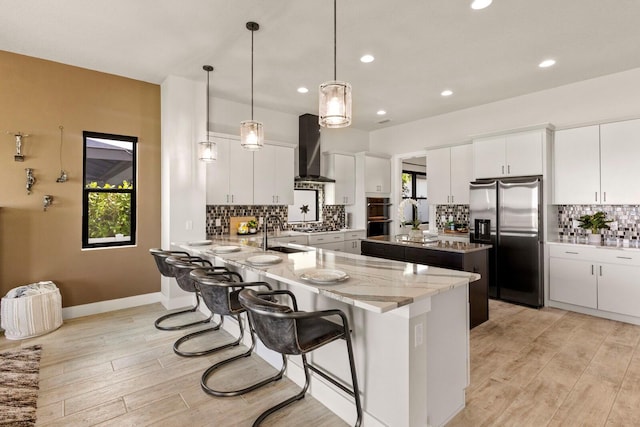 kitchen featuring stainless steel appliances, sink, white cabinets, and wall chimney exhaust hood