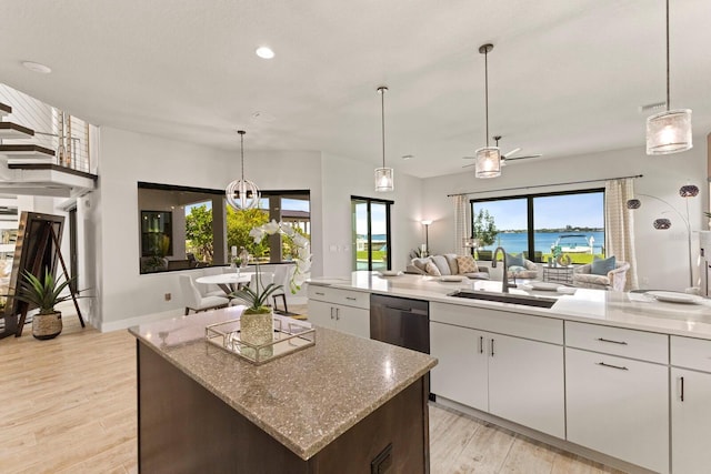 kitchen featuring sink, dishwasher, white cabinetry, a center island, and a water view