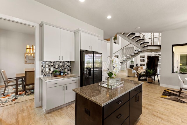 kitchen featuring dark brown cabinetry, stainless steel fridge with ice dispenser, light stone countertops, and white cabinets