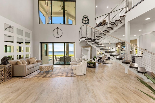 living room featuring a water view, a towering ceiling, and hardwood / wood-style flooring