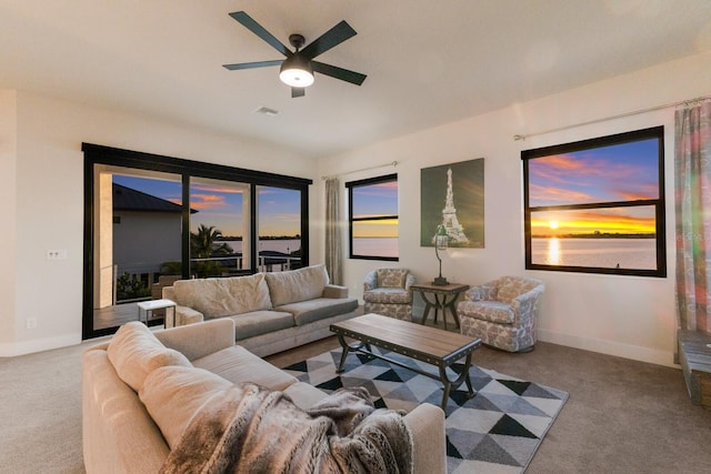 living room with a water view, light carpet, and ceiling fan