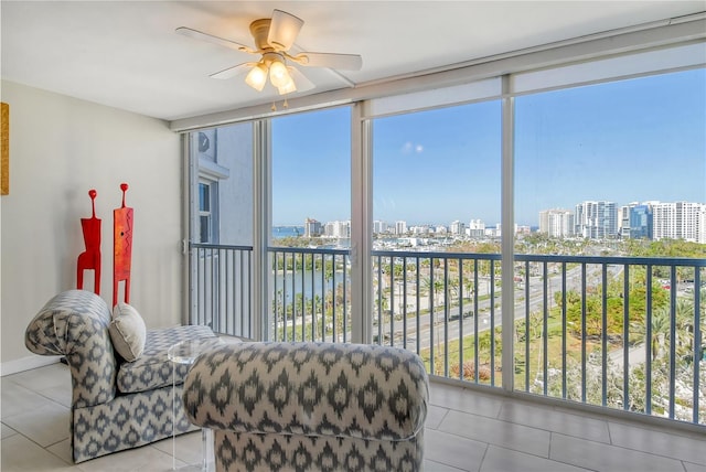 sunroom / solarium with plenty of natural light, ceiling fan, and a water view