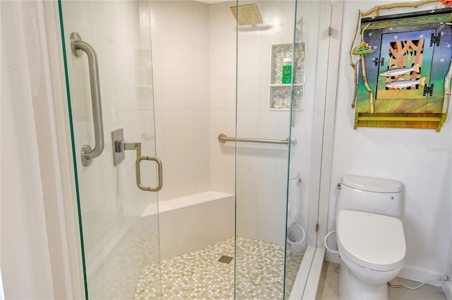 bathroom featuring a shower with door and toilet