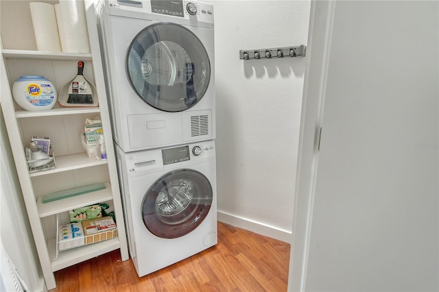 clothes washing area featuring hardwood / wood-style flooring and stacked washer and dryer