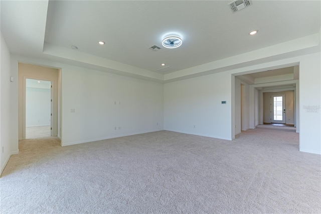 empty room with light carpet and a tray ceiling