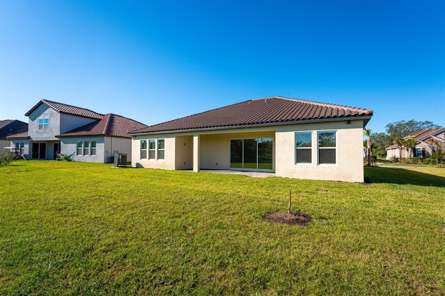 rear view of property featuring central AC unit and a lawn