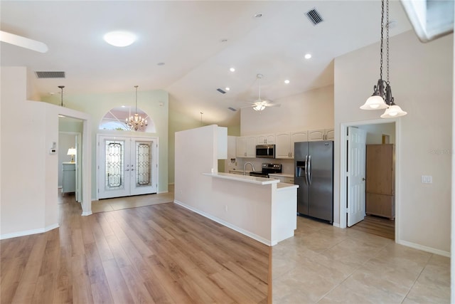 kitchen with appliances with stainless steel finishes, hanging light fixtures, high vaulted ceiling, white cabinets, and kitchen peninsula