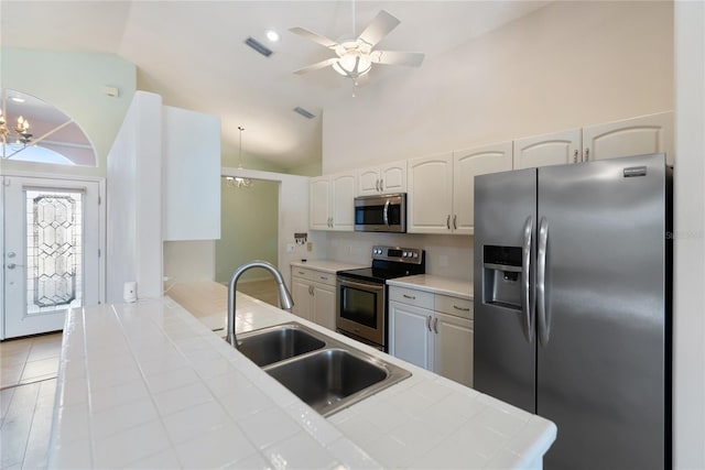 kitchen with ceiling fan with notable chandelier, tile countertops, white cabinetry, sink, and stainless steel appliances