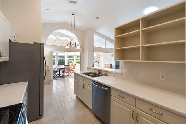 kitchen featuring sink, vaulted ceiling, hanging light fixtures, light tile patterned floors, and appliances with stainless steel finishes