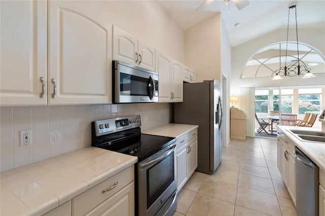 kitchen featuring appliances with stainless steel finishes, pendant lighting, white cabinets, backsplash, and tile counters