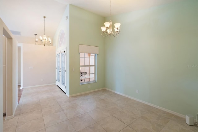 tiled empty room featuring a high ceiling and an inviting chandelier