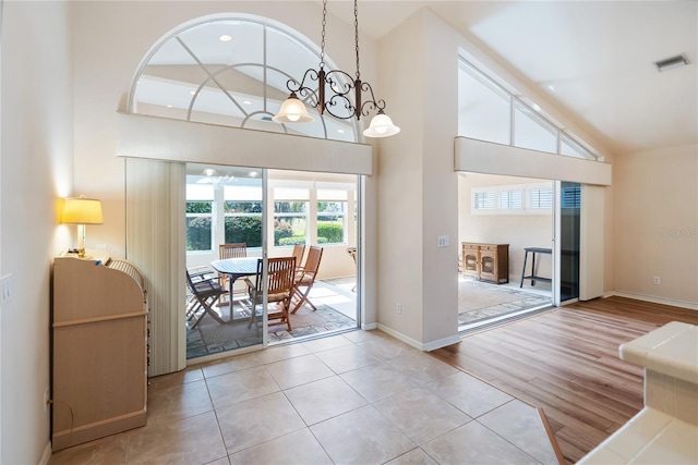 doorway featuring light hardwood / wood-style flooring, high vaulted ceiling, and a chandelier