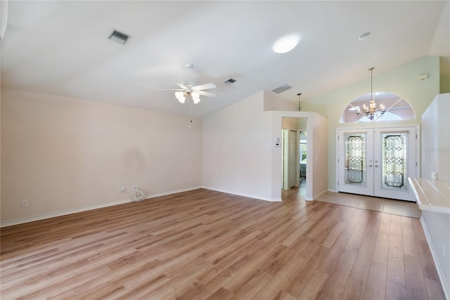 foyer entrance with vaulted ceiling, ceiling fan with notable chandelier, light hardwood / wood-style floors, and french doors