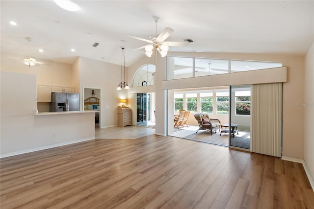 unfurnished living room featuring high vaulted ceiling, light hardwood / wood-style floors, and ceiling fan