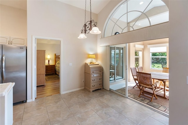 dining space with light tile patterned floors and high vaulted ceiling