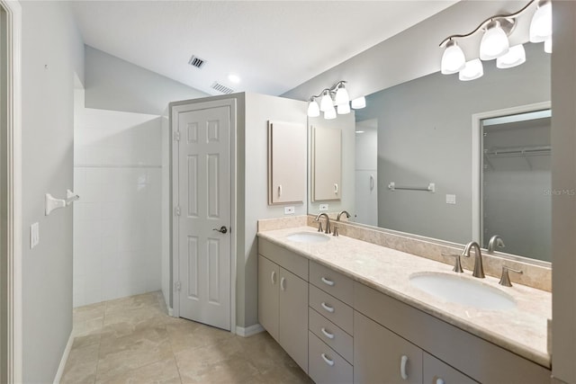 bathroom with lofted ceiling, vanity, tile patterned floors, and walk in shower