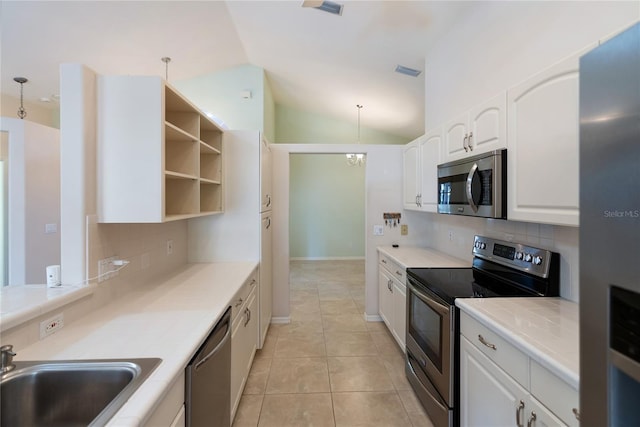 kitchen with appliances with stainless steel finishes, white cabinetry, lofted ceiling, sink, and hanging light fixtures