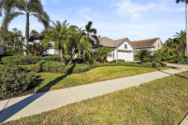 view of front of property featuring a garage, a tile roof, and a front lawn