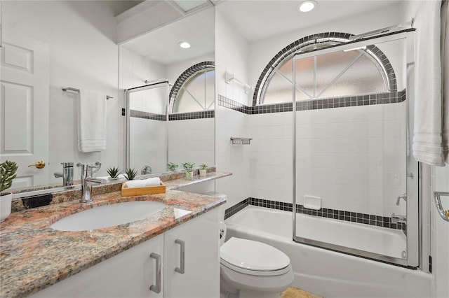 bathroom with recessed lighting, shower / bath combination with glass door, vanity, and toilet