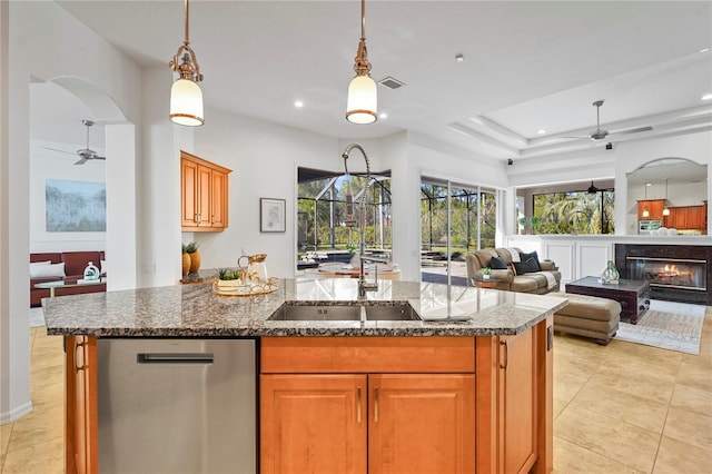 kitchen with a kitchen island with sink, pendant lighting, open floor plan, and stainless steel dishwasher