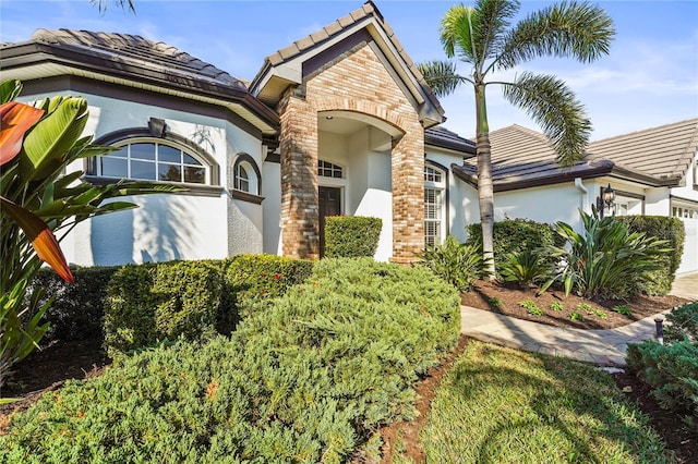 view of front of house featuring a tiled roof, an attached garage, and stucco siding