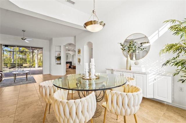 dining space featuring arched walkways, ceiling fan, light tile patterned flooring, visible vents, and baseboards