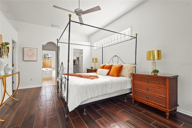 bedroom with wood tiled floor, arched walkways, baseboards, and ensuite bathroom