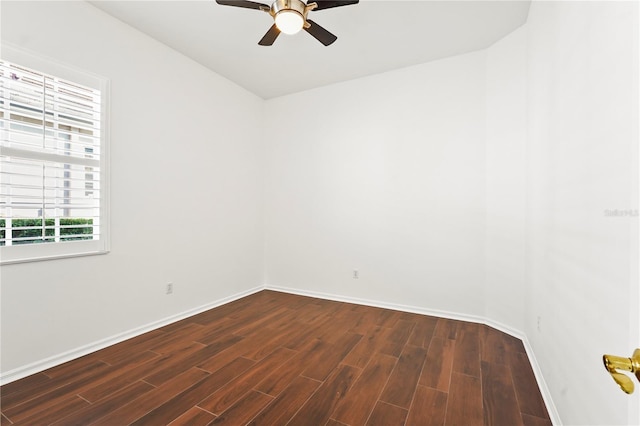 spare room with dark wood-style floors, a ceiling fan, and baseboards