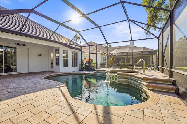 view of swimming pool with a pool with connected hot tub, glass enclosure, a patio, and ceiling fan