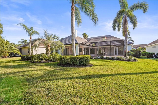 rear view of property with a yard and a lanai