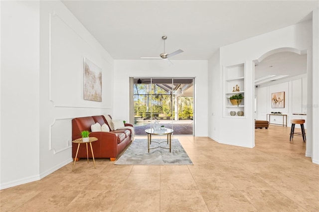 sitting room with light tile patterned floors, built in features, baseboards, a sunroom, and ceiling fan